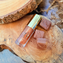 Cargar imagen en el visor de la galería, Lip Gloss artesanal Choco Kiss sobre madera con chocolates - Hidratación y brillo sabor a chocolate.
