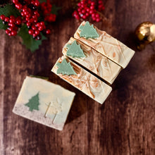 Cargar imagen en el visor de la galería, Jabones artesanales navideños de Tt atelier, decorados con árboles de Navidad y detalles dorados, colocados sobre una mesa rústica con elementos festivos.