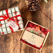 Cargar imagen en el visor de la galería, Caja navideña abierta con barra de jabón artesanal envuelta en papel kraft.