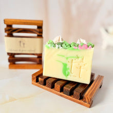 Cargar imagen en el visor de la galería, Vista frontal de jabonera cóncava color caoba con barra de jabón decorativa encima, fondo claro. Otra jabonera desenfocada al fondo con banda de papel.