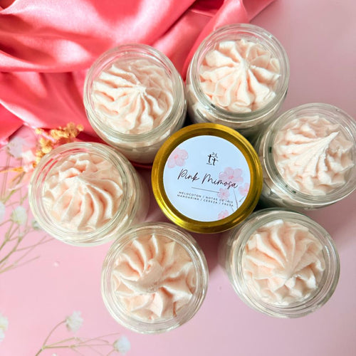 Scrubs artesanales Pink Mimosa en envases circulares, dispuestos en forma de flor sobre fondo rosado. Exfoliante espumoso con aroma frutal.