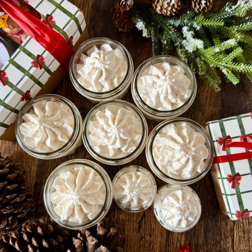 Varios frascos de whipped body butter navideño con decoración batida en la parte superior, estilo festivo.