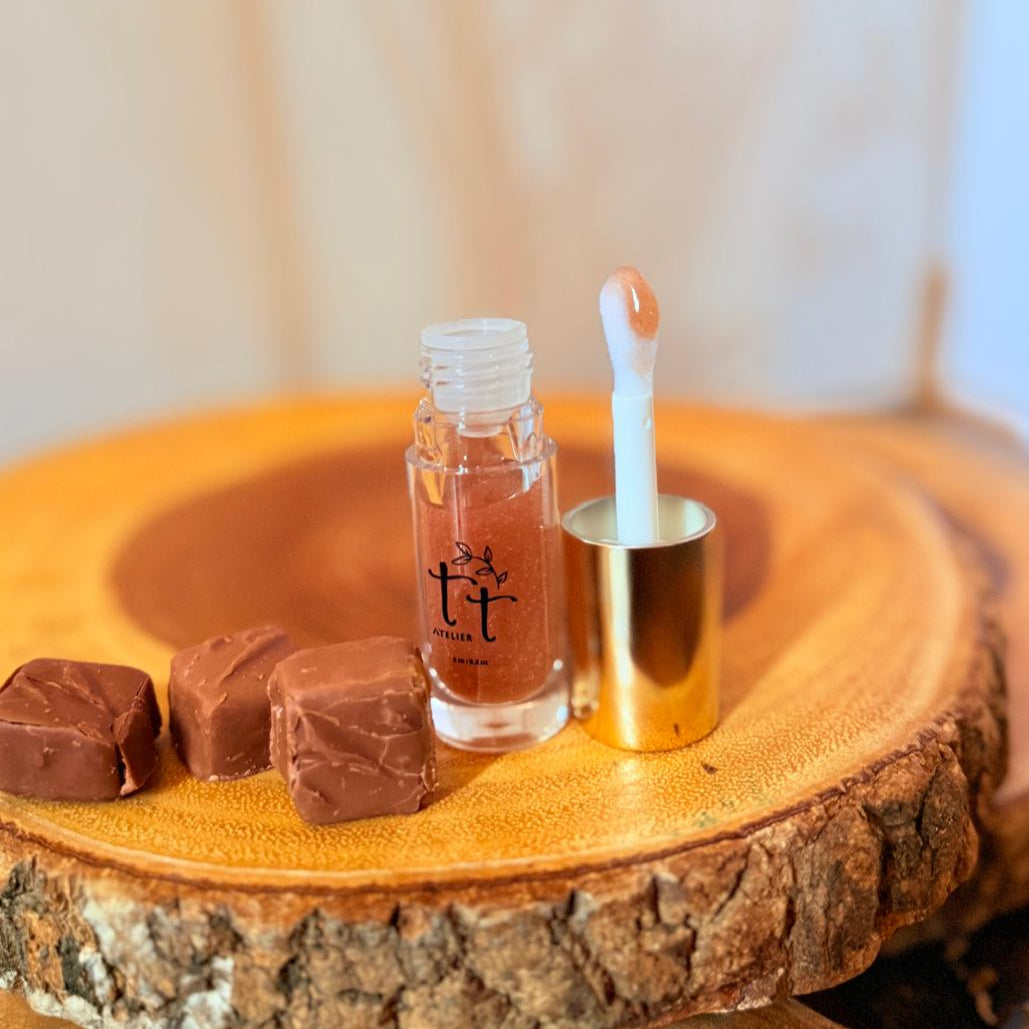 Lip Gloss Choco Kiss abierto con aplicador y chocolates al lado - Brillo marrón cálido hecho a mano por Tt atelier.