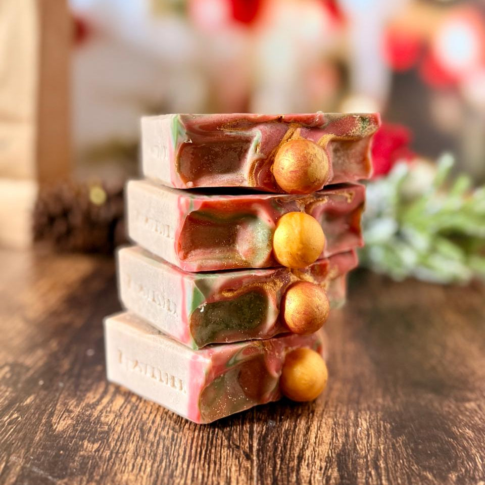 Jabones artesanales navideños apilados con detalle de esfera dorada.