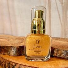 Cargar imagen en el visor de la galería, Aceite corporal iluminador Lumière Gold en frasco de vidrio con pump dorado y tapa transparente, sobre base de madera.
