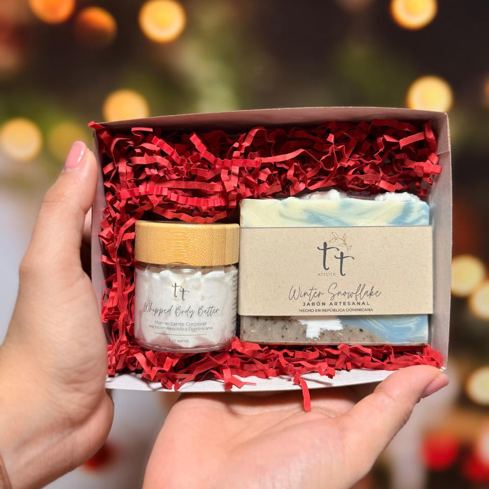 Caja abierta sostenida con dos manos, en su interior una barra de jabón de colección y una mini whipped body butter.